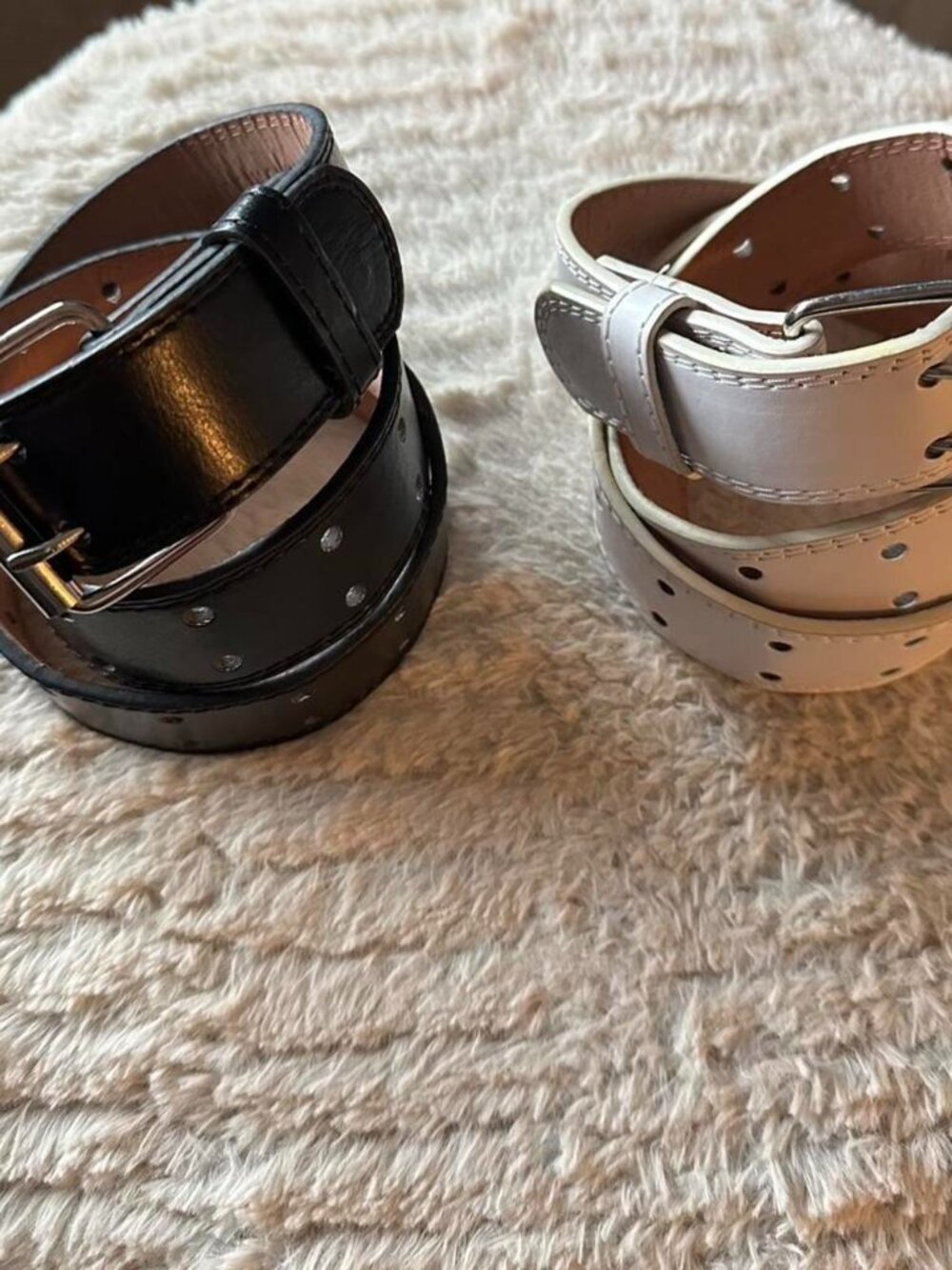 Set of 2 black and white leather belts with silver buckles.